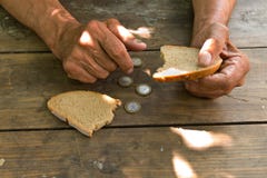 Overhandigt de slechte oude man ` s, stuk van brood en verandering, pence op houten achtergrond royalty-vrije stock foto Overhandigt de slechte oude man ` s, stuk van brood en verandering, pence op houten achtergrond royalty-vrije stock foto