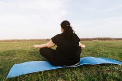 Overweight woman meditating at yoga mat outdoors royalty free stock photography Overweight woman meditating at yoga mat outdoors royalty free stock photography