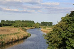 Overweldigend panorama op de gebieden bij een zonnige dag met een kanaal en bomen stock fotografie Overweldigend panorama op de gebieden bij een zonnige dag met een kanaal en bomen stock fotografie