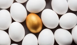 Одно золотое яйцо среди белых яя на серой предпосылке стоковое изображение Одно золотое яйцо среди белых яя на серой предпосылке стоковое изображение