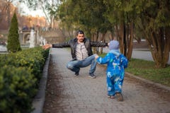 Отец и меньший сын имея потеху совместно: Маленький малыш мальчик бежит в его парк отца весной, папу готов обнять его стоковое фото Отец и меньший сын имея потеху совместно: Маленький малыш мальчик бежит в его парк отца весной, папу готов обнять его стоковое фото