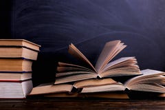 Открытые книги стог на столе, на фоне доски мела Трудная домашняя работа в школе, гора знания стоковые изображения Открытые книги стог на столе, на фоне доски мела Трудная домашняя работа в школе, гора знания стоковые изображения