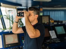 Офицер во время навигационного дозора смотря через бинокли стоковая фотография Офицер во время навигационного дозора смотря через бинокли стоковая фотография