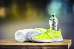 Paar geelgroene van het de handdoekwater van sportschoenen slimme pone en hoofdtelefoons op houten raad In de achtergrondbos of p royalty-vrije stock foto Paar geelgroene van het de handdoekwater van sportschoenen slimme pone en hoofdtelefoons op houten raad In de achtergrondbos of p royalty-vrije stock foto