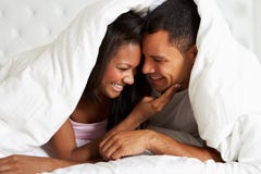 Paar het Ontspannen in Bed het Verbergen onder Dekbed royalty-vrije stock foto's Paar het Ontspannen in Bed het Verbergen onder Dekbed royalty-vrije stock foto's