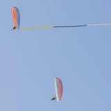 Paar leichtsinnige Piloten führt Luftakrobatik an Bord der paramotors mit dem Gebrauch einer Fahne durch stockfoto Paar leichtsinnige Piloten führt Luftakrobatik an Bord der paramotors mit dem Gebrauch einer Fahne durch stockfoto