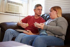 Paar met Slechte Dieetzitting op Sofa Eating Meal royalty-vrije stock foto Paar met Slechte Dieetzitting op Sofa Eating Meal royalty-vrije stock foto