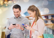 Paar met smartphones en het winkelen zakken in wandelgalerij royalty-vrije stock foto's Paar met smartphones en het winkelen zakken in wandelgalerij royalty-vrije stock foto's