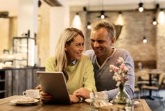 Paare, die etwas auf digitaler Tablette besprechen lizenzfreies stockbild Paare, die etwas auf digitaler Tablette besprechen lizenzfreies stockbild