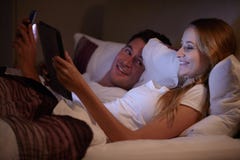 Paare, die im Bett unter Verwendung Digital-Tablets und -Handys liegen stockbild Paare, die im Bett unter Verwendung Digital-Tablets und -Handys liegen stockbild