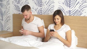 Paare mit Smartphones im Bett stock footage Paare mit Smartphones im Bett stock footage