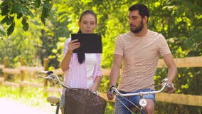 Paare mit Tabletten-PC und -fahrrädern am Sommer parken stock footage Paare mit Tabletten-PC und -fahrrädern am Sommer parken stock footage