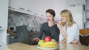 Paare unter Verwendung des Computers an der Küchenarbeitsplatte stock footage Paare unter Verwendung des Computers an der Küchenarbeitsplatte stock footage