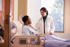 Paciente femenino del doctor Talking To Male en cama de hospital imágenes de archivo libres de regalías Paciente femenino del doctor Talking To Male en cama de hospital imágenes de archivo libres de regalías