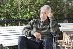 Paciente masculino mayor pensativo que se sienta en silla de ruedas en el césped fotografía de archivo libre de regalías Paciente masculino mayor pensativo que se sienta en silla de ruedas en el césped fotografía de archivo libre de regalías