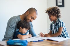 Padre che aiuta i suoi figli con compito Fotografie Stock Padre che aiuta i suoi figli con compito Fotografie Stock