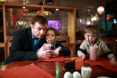 Padre con dos hijos que beben el batido de leche fotografía de archivo libre de regalías Padre con dos hijos que beben el batido de leche fotografía de archivo libre de regalías