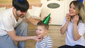 Padre della famiglia felice che celebra compleanno che mette sul cappello a suo figlio a casa fotografia stock Padre della famiglia felice che celebra compleanno che mette sul cappello a suo figlio a casa fotografia stock