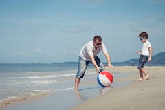 Padre e figlio con la palla che gioca a calcio sulla spiaggia al giorno immagini stock libere da diritti Padre e figlio con la palla che gioca a calcio sulla spiaggia al giorno immagini stock libere da diritti