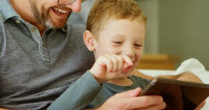 Padre e hijo que usa la tableta digital en el sofá en casa 4k metrajes Padre e hijo que usa la tableta digital en el sofá en casa 4k metrajes