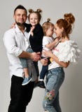 Padre feliz de la madre de la familia y dos muchachas de la hija que sonríen en estudio gris imagen de archivo Padre feliz de la madre de la familia y dos muchachas de la hija que sonríen en estudio gris imagen de archivo