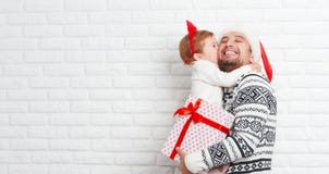 Padre y niño felices de la familia con el regalo en beso de la Navidad Imagenes de archivo Padre y niño felices de la familia con el regalo en beso de la Navidad Imagenes de archivo