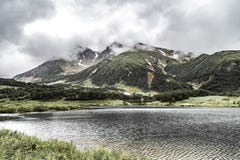 Paesaggio con le pianure verdi e lago sulla penisola di Kamchatka, Russia fotografia stock Paesaggio con le pianure verdi e lago sulla penisola di Kamchatka, Russia fotografia stock