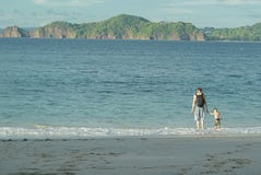 Pai com uma trouxa que guarda a mão de seu filho pelo mar Entram na água contra o contexto de ilhas bonitas fotos de stock Pai com uma trouxa que guarda a mão de seu filho pelo mar Entram na água contra o contexto de ilhas bonitas fotos de stock