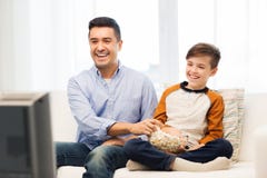 Pai e filho de sorriso que olham a tevê em casa imagens de stock Pai e filho de sorriso que olham a tevê em casa imagens de stock