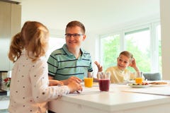 Pai feliz com suas crianças que falam no café da manhã em casa foto de stock Pai feliz com suas crianças que falam no café da manhã em casa foto de stock