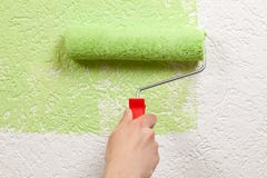 Painter paints a wall with a paint roller