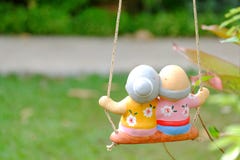 A pair of small beautiful old man and woman statues sitting on a swing stock photography A pair of small beautiful old man and woman statues sitting on a swing stock photography
