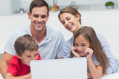 Pais e crianças alegres que usam um portátil fotos de stock Pais e crianças alegres que usam um portátil fotos de stock