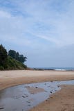 Paisagem da praia com uma boca de rio e um penhasco verde fotografia de stock Paisagem da praia com uma boca de rio e um penhasco verde fotografia de stock