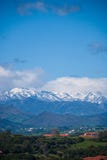 A paisagem vertical do vale com casas e com o Picos de Europa nevou no fundo imagens de stock A paisagem vertical do vale com casas e com o Picos de Europa nevou no fundo imagens de stock