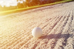 Palla da golf bianca del fuoco selettivo sul bunker della sabbia con il fi verde fotografie stock libere da diritti Palla da golf bianca del fuoco selettivo sul bunker della sabbia con il fi verde fotografie stock libere da diritti