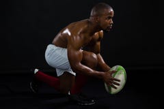 Palla di rugby senza camicia della tenuta dell'uomo di vista laterale fotografie stock libere da diritti Palla di rugby senza camicia della tenuta dell'uomo di vista laterale fotografie stock libere da diritti