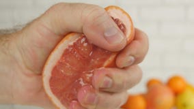 Pampelmusen-Abschluss herauf Bild mit Handpressen-Hälfte der Frucht und den Saft zusammendrücken lizenzfreie stockbilder Pampelmusen-Abschluss herauf Bild mit Handpressen-Hälfte der Frucht und den Saft zusammendrücken lizenzfreie stockbilder