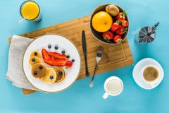 Pancakes With Berries On Kitchen Desk With Coffee And Orange Juice Pancakes With Berries On Kitchen Desk With Coffee And Orange Juice