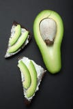 Pane tostato di pane nero e dei pezzi di avocado su un fondo nero, verticalmente fotografia stock libera da diritti Pane tostato di pane nero e dei pezzi di avocado su un fondo nero, verticalmente fotografia stock libera da diritti
