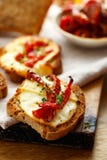Pani tostati con il formaggio affumicato del latte di pecore, i pomodori seccati al sole e le erbe immagini stock libere da diritti Pani tostati con il formaggio affumicato del latte di pecore, i pomodori seccati al sole e le erbe immagini stock libere da diritti