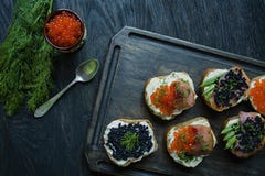 Panini con il caviale rosso e nero Primo piano Priorit? bassa di legno scura fotografie stock Panini con il caviale rosso e nero Primo piano Priorit? bassa di legno scura fotografie stock