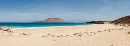 Panorama av den Playa de las Conchas stranden med blå hav- och vitsand La Graciosa, Lanzarote, kanariefågelöar, Spanien arkivfoton Panorama av den Playa de las Conchas stranden med blå hav- och vitsand La Graciosa, Lanzarote, kanariefågelöar, Spanien arkivfoton