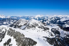 Panorama brilhante das cordilheiras com neve e gelo nas partes superiores contra o céu azul no inverno e em florestas densas fotos de stock royalty free Panorama brilhante das cordilheiras com neve e gelo nas partes superiores contra o céu azul no inverno e em florestas densas fotos de stock royalty free