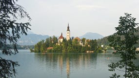 Panoramablick über dem See geblutet, Julian Alps und Kirche auf der Insel, sonniger Tag, geblutet, Slowenien lizenzfreies stockbild Panoramablick über dem See geblutet, Julian Alps und Kirche auf der Insel, sonniger Tag, geblutet, Slowenien lizenzfreies stockbild