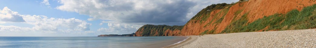 A Panoramic view of the cliffs at Sidmouth in Devon, showing the stone shore and the oxidised cliffs in the bay stock photography A Panoramic view of the cliffs at Sidmouth in Devon, showing the stone shore and the oxidised cliffs in the bay stock photography