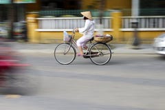Panorerat skott som visar en kvinna som cyklar i Vietnam arkivfoto Panorerat skott som visar en kvinna som cyklar i Vietnam arkivfoto