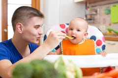 Papa die zijn baby voeden bij keuken royalty-vrije stock foto Papa die zijn baby voeden bij keuken royalty-vrije stock foto