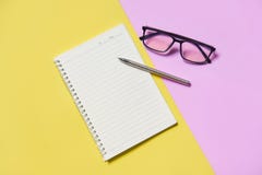 Papel de la libreta o del cuaderno con la pluma y vidrios en rosa amarillo fotos de archivo libres de regalías Papel de la libreta o del cuaderno con la pluma y vidrios en rosa amarillo fotos de archivo libres de regalías