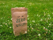A paper bag with handwritten words `Go to zero waste` on it among clover and green grass with copy space. stock image A paper bag with handwritten words `Go to zero waste` on it among clover and green grass with copy space. stock image